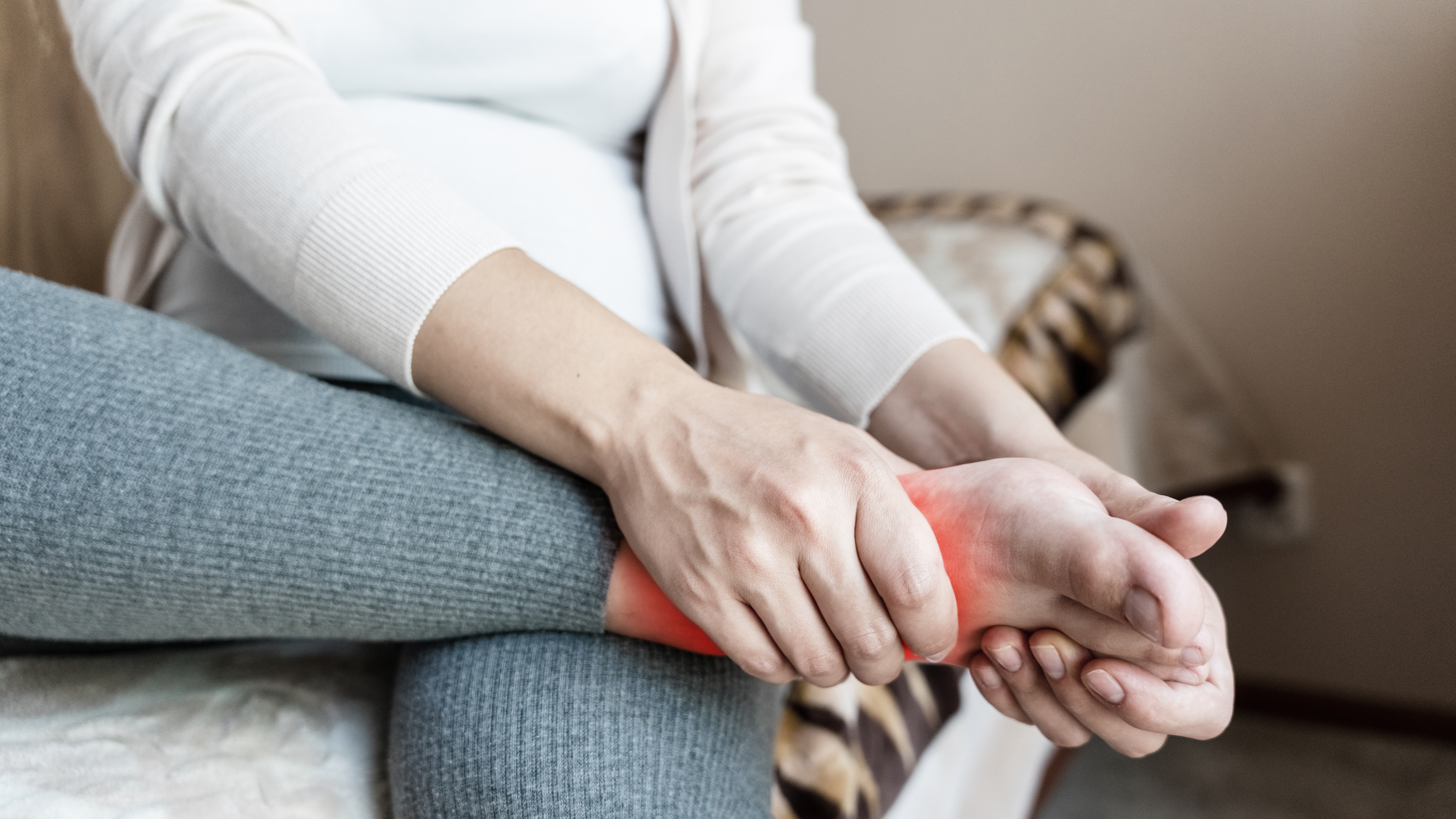 Frau greift sich an das schmerzende Sprunggelenk