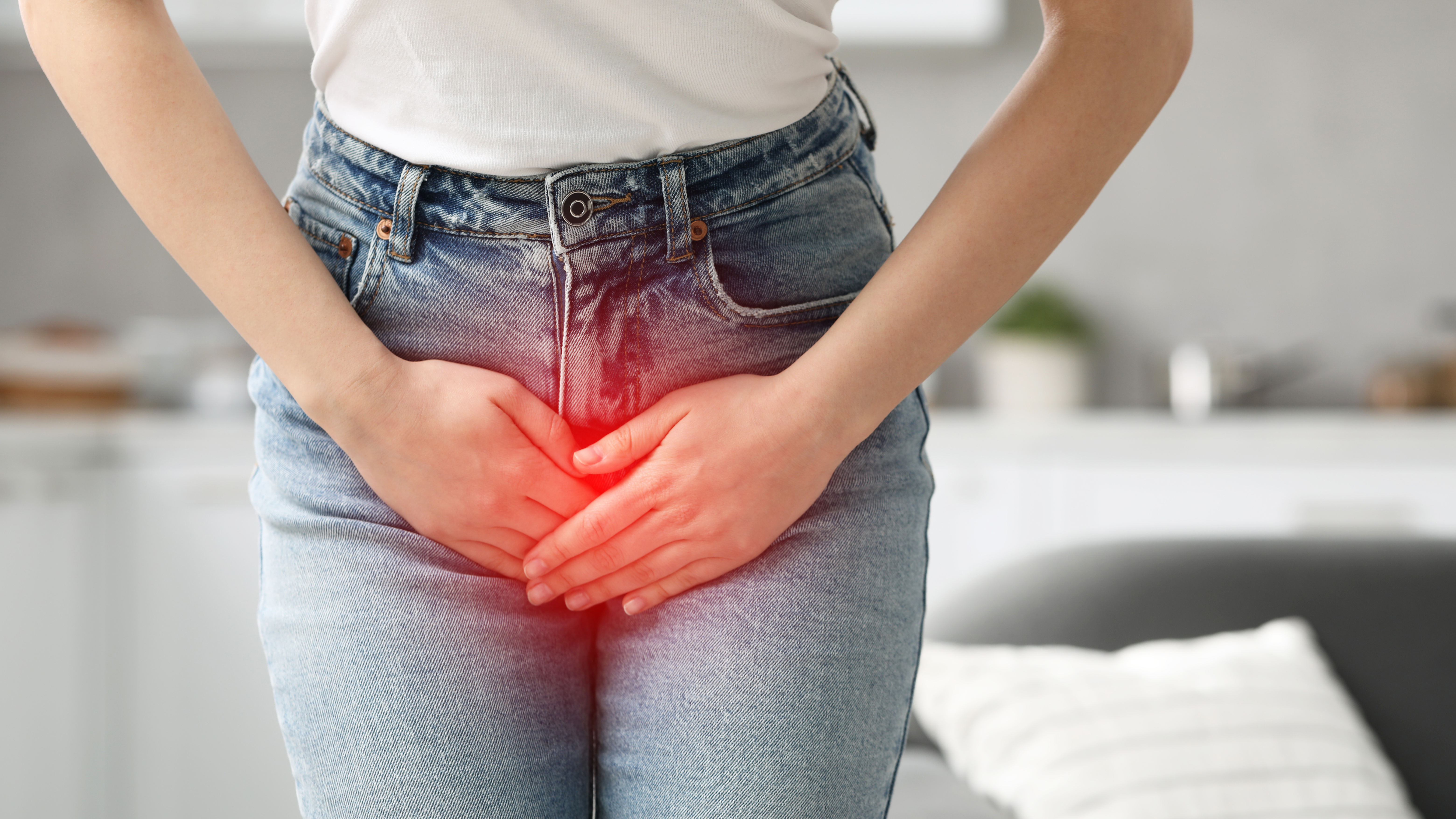 Frau greift sich aufgrund von Inkontinenz an den Unterleib