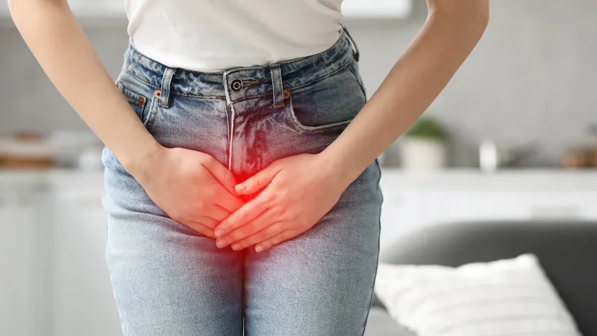 Frau greift sich aufgrund von Inkontinenz an den Unterleib