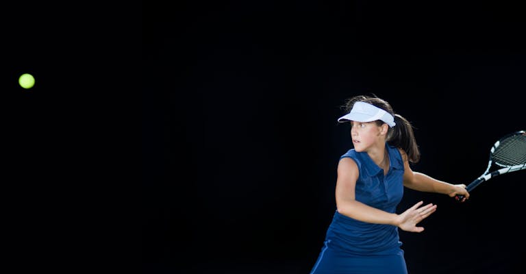 Frau spielt vor schwarzem Hintergrund Tennis