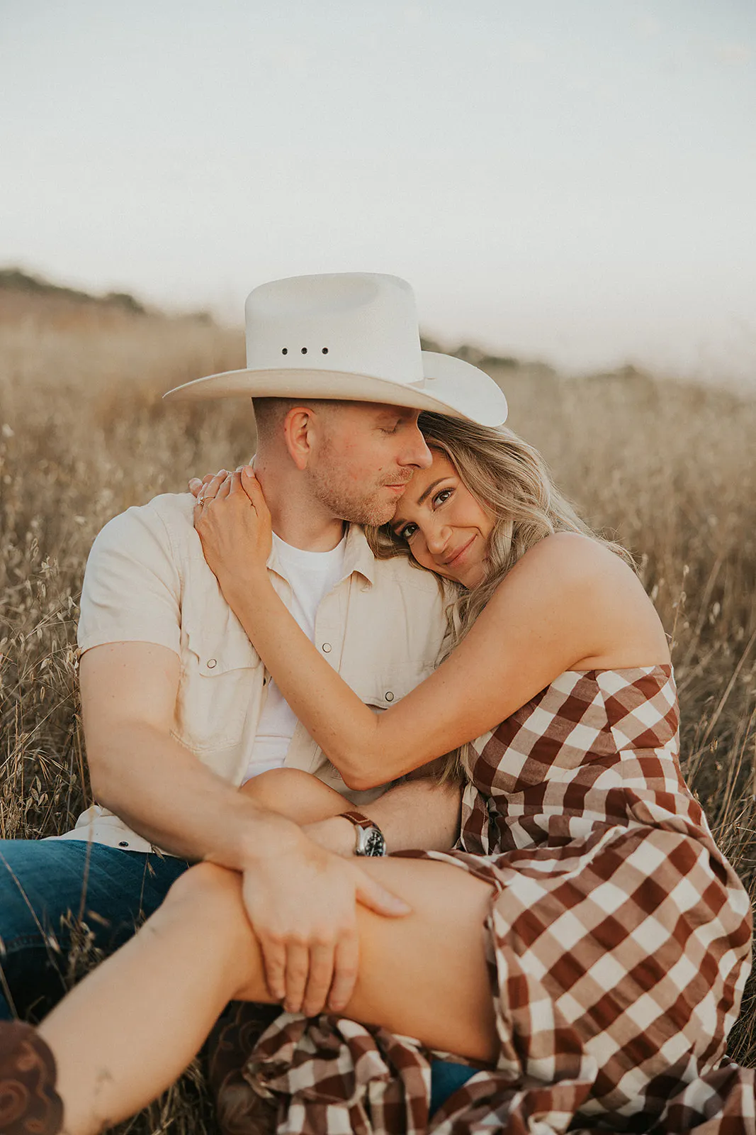 Couple cuddled up in a field in a western chic attire, in Montana