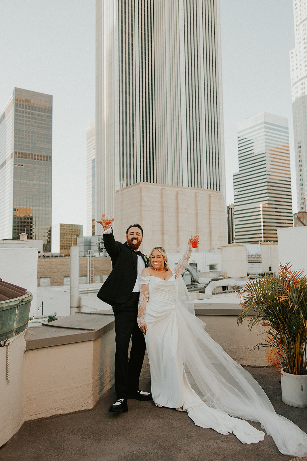Couple sharing a cheers after getting married on a rooftop in DTLA at The Oviatt Penthouse