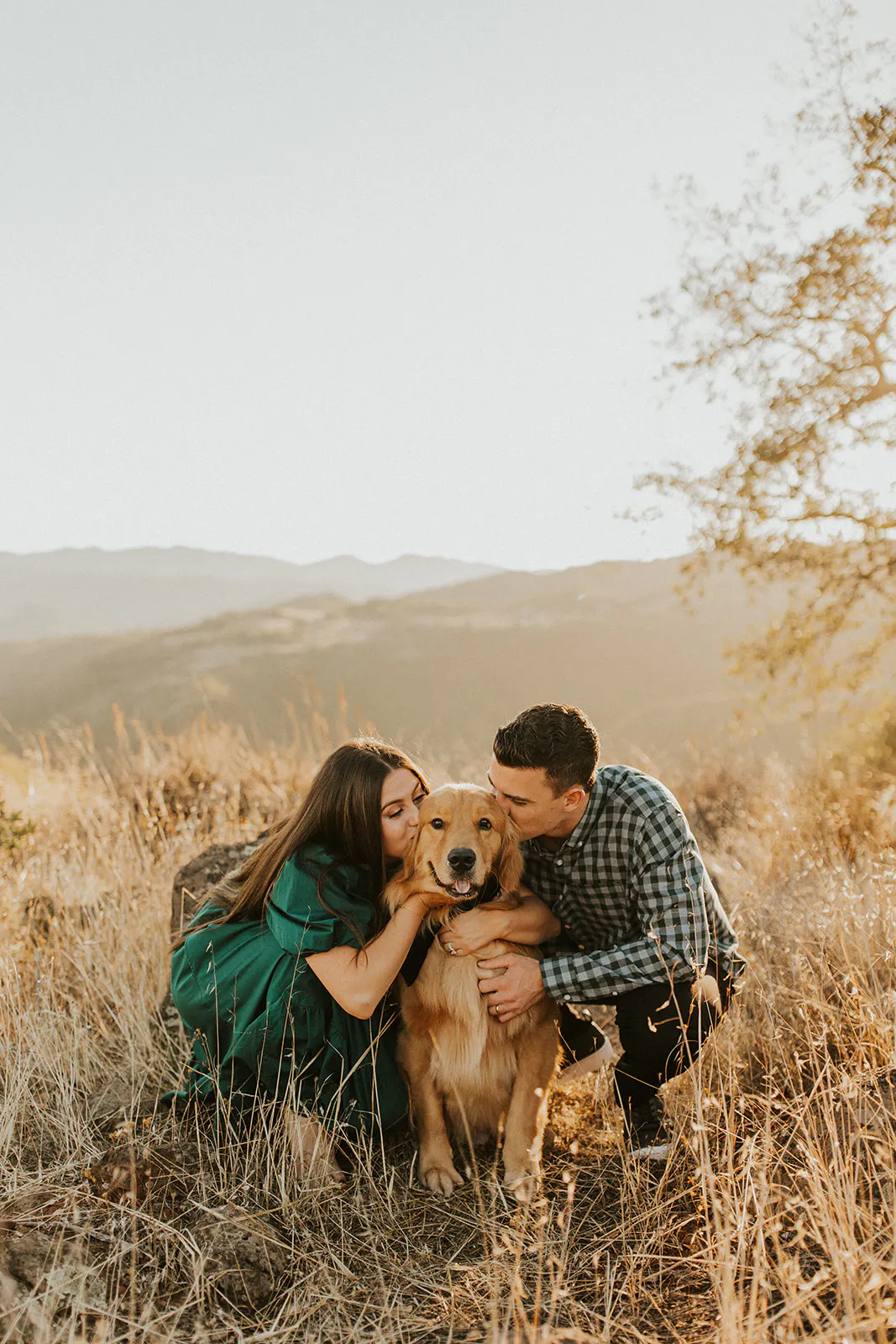 couple kissing their golden retriever in san diego mountains