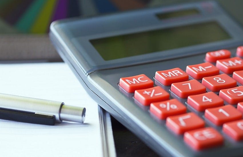 calculatrice à côte d'une feuille blanche et d'un stylo