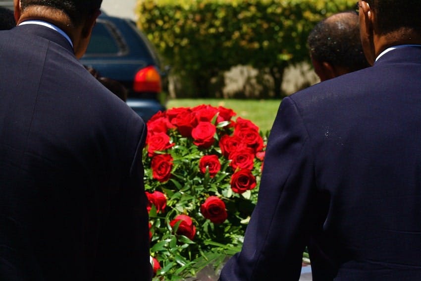 porteur qui tiennent cercueil avec coussin de roses rouges dans cimetière