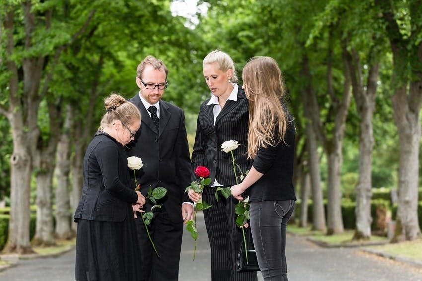 deux adultes et deux enfants tenant des roses rouges et blanches dans un cimetière