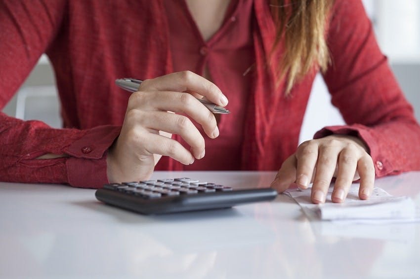 femme faisant des calculs avec une calculatrice et stylo devant une facture