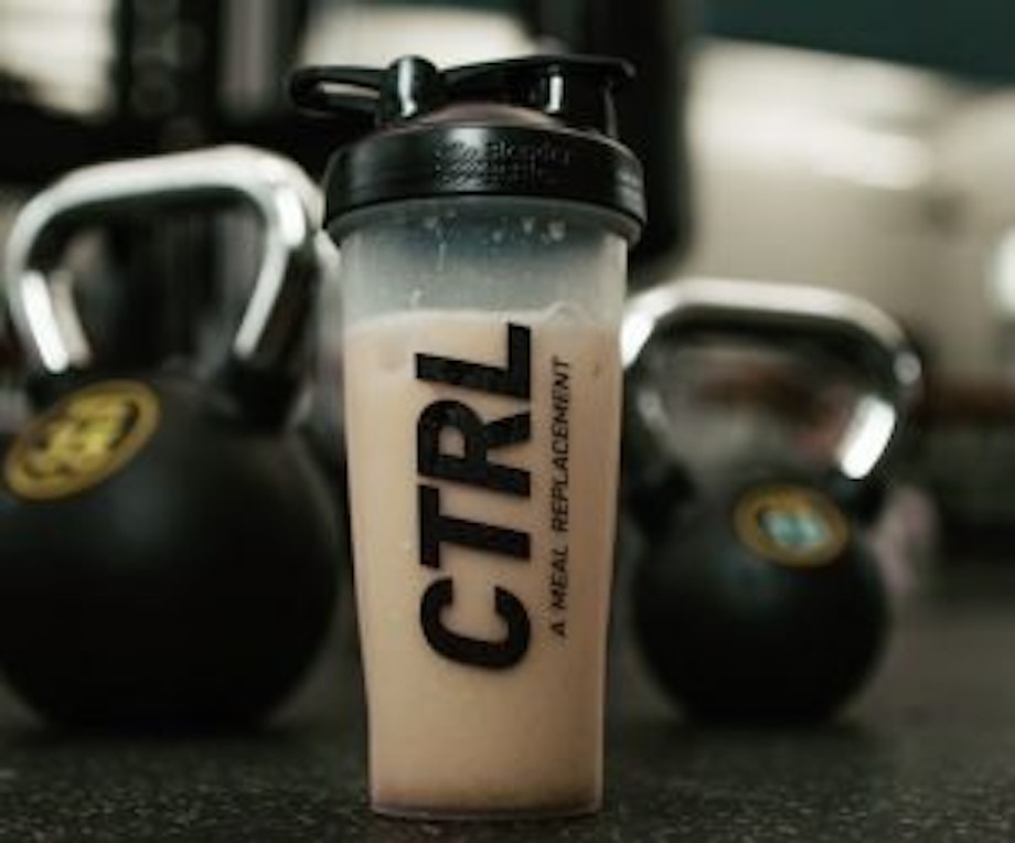 Ein CTRL-Proteinshake steht auf dem Boden in einem Fitness-Studio