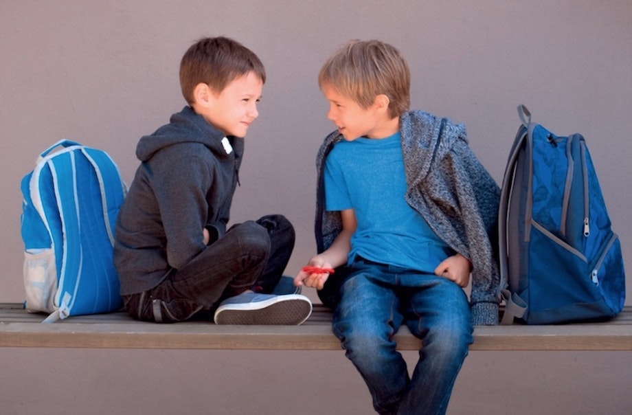 Zwei Jungs sitzen auf eine Bank und reden. Mit dem E-Book des Friedrich Verlags lernen Kinder in der Grundschule aktiv zuzuhören, was eine Kernkomponente der gewaltfreien Kommunikation darstellt.