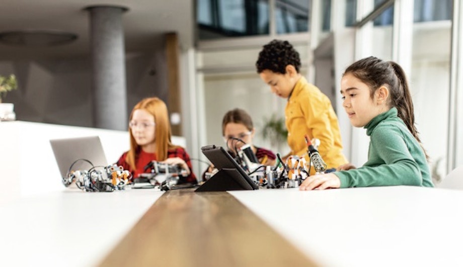 Schüler und Schülerinnen sitzen gemeinsam am Tisch und führen ein Experiment durch