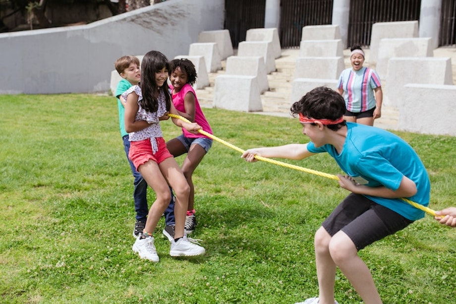 Kinder spielen Tauziehen auf einer Wiese