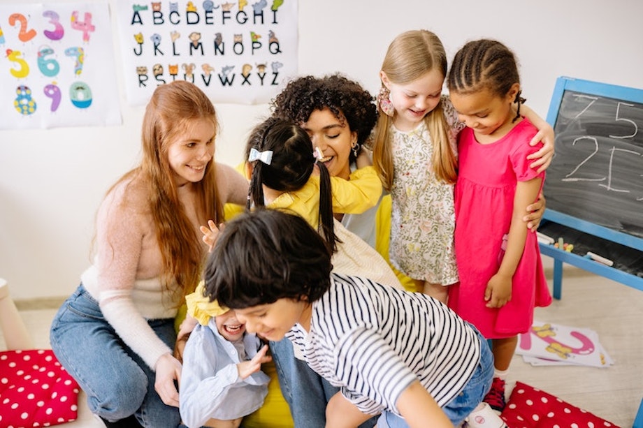 Zwei Lehrerinnen fördern Differenzierung im Unterricht, sie lachen und spielen mit ihren SchülerInnen