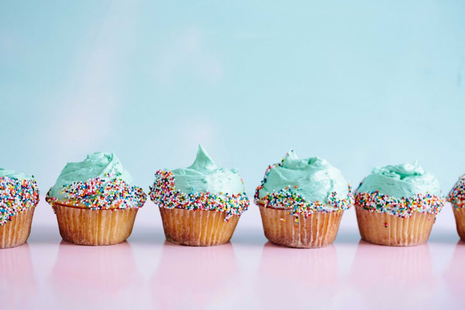 Cupcakes mit türkisem Topping auf einem rosa Untergrund.