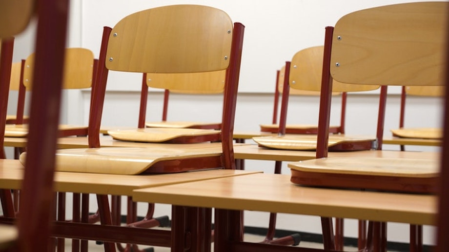 Stühle stehen in einem Klassenzimmer hochgeräumt auf den Tischen. Ruhigere Zeiten im Schulbetrieb wie Freistunden kannst du auch für Korrekturen nutzen, statt mit den Kollegen und Kolleginnen Kaffee zu trinken.