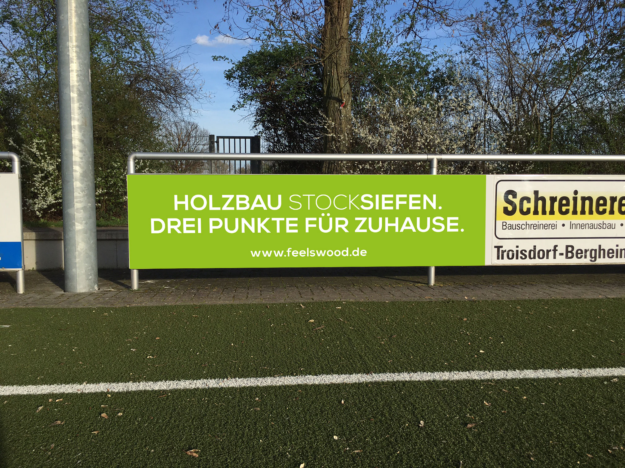 Grün/Weiße Sportplatzbande mit dem Claim "Drei Punkte für Zuhause" des Unternehmens Stocksiefen - Handwerk Marketing von der Meisterstück Agency aus Köln.