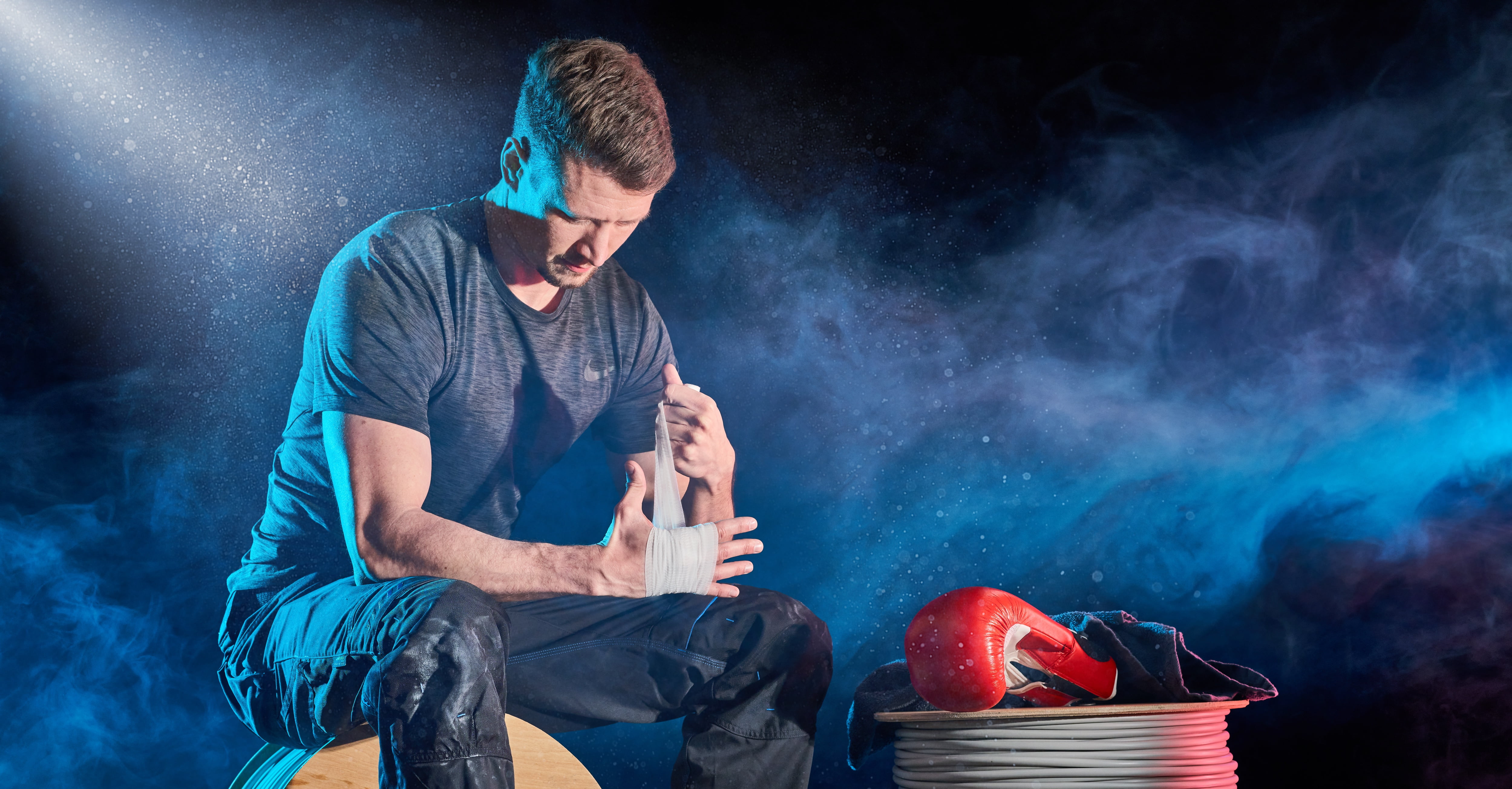 Ein Mann bindet sich ein Tape um die Hand während neben Ihm Boxhandschuhe liegen - Werbeagentur Handwerk, von der  Meisterstück Agency aus Köln