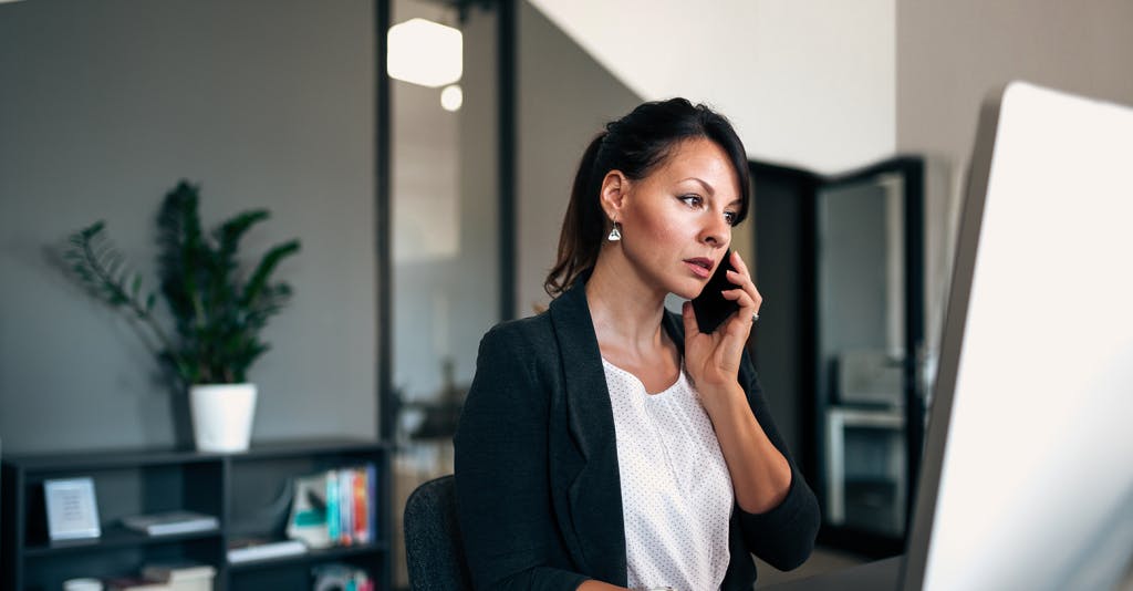woman on the phone and looking at a computer screen