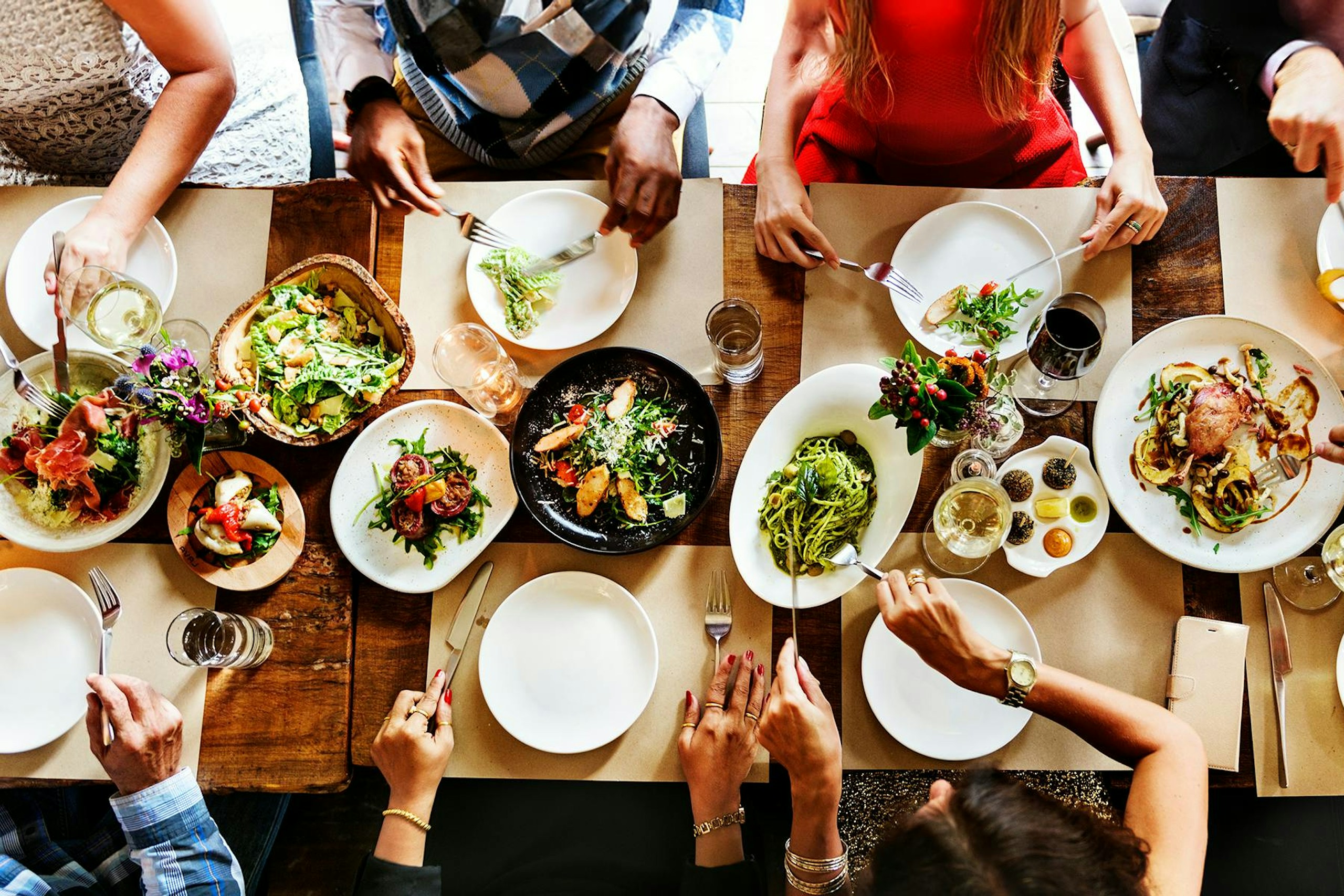 People seated at a dining table full of plates of food in this image for Meltwater's 2024 Consumer Insights: Food & Beverage report