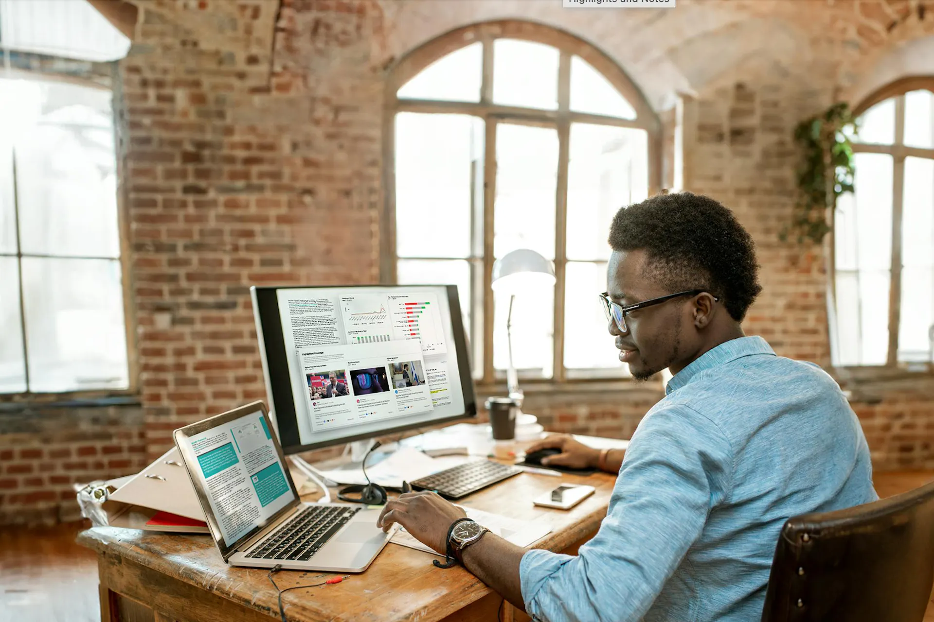 Image of a PR professional sitting at his desk in front of a large monitor and laptop. The computers show various charts and tools for PR professionals. PR Toolkit download
