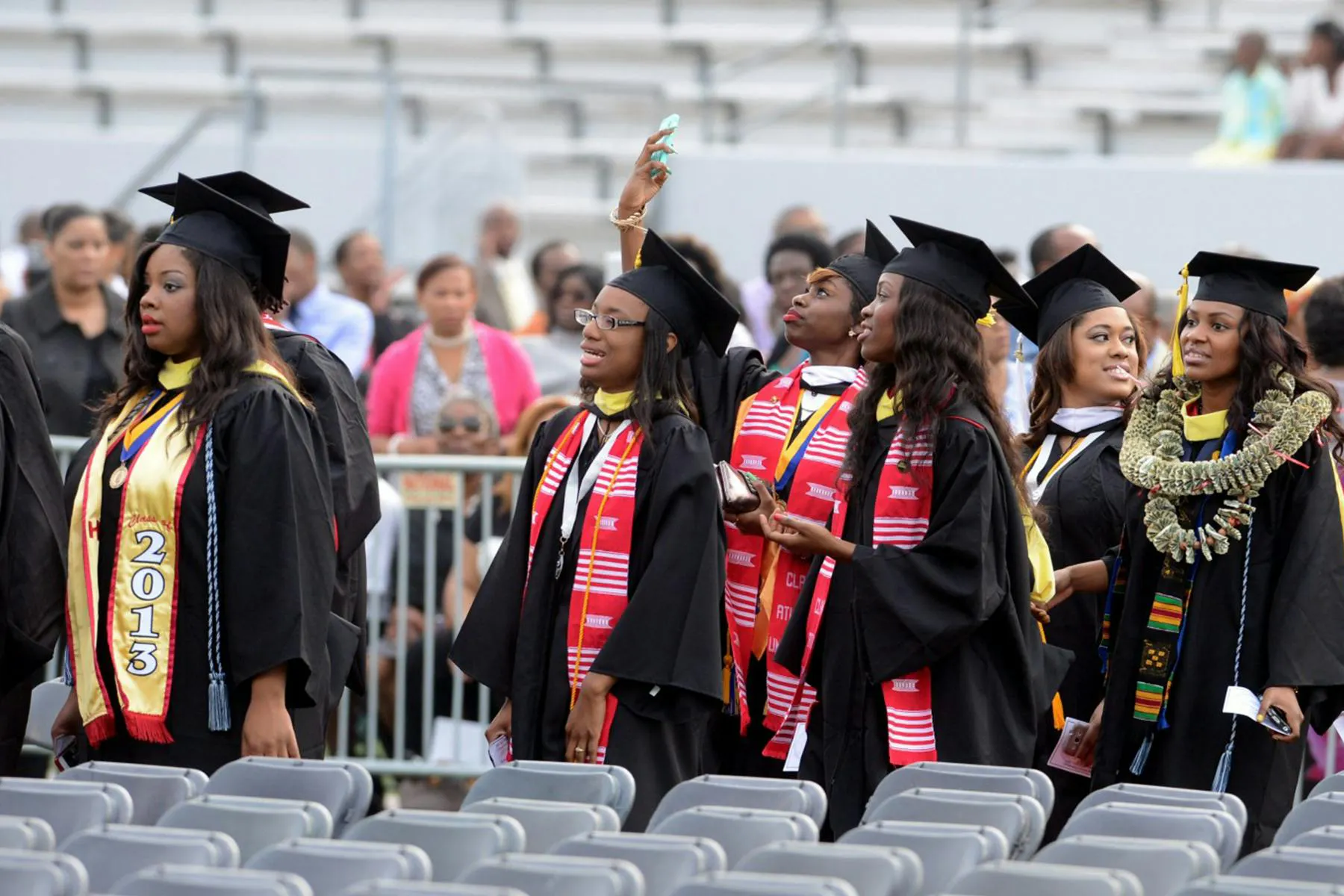 An image of African-American students in graduation robes walking between aisles of chairs for a Meltwater customer story about UNCF.