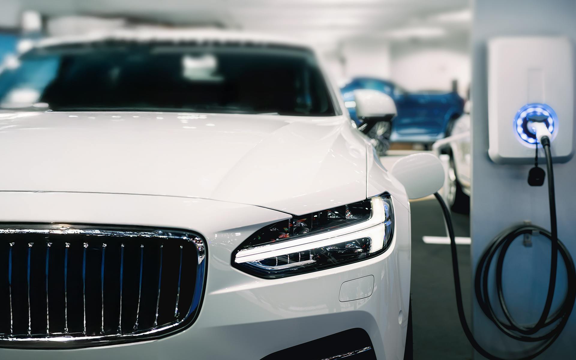 A white car plugged into a silver white charging station for Meltwater's Consumer Insights: Electric Vehicles report.
