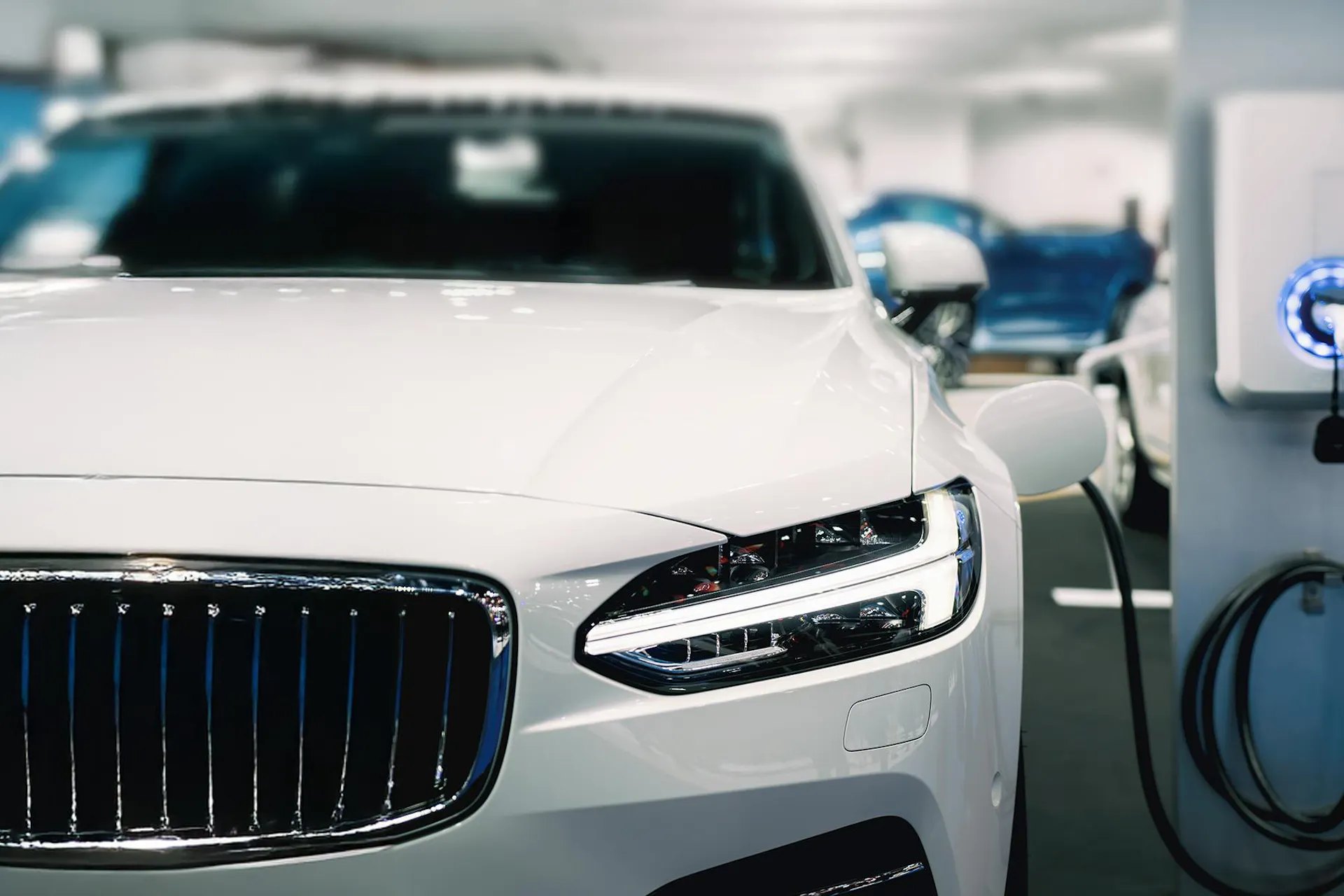 A white car plugged into a silver white charging station for Meltwater's Consumer Insights: Electric Vehicles report.