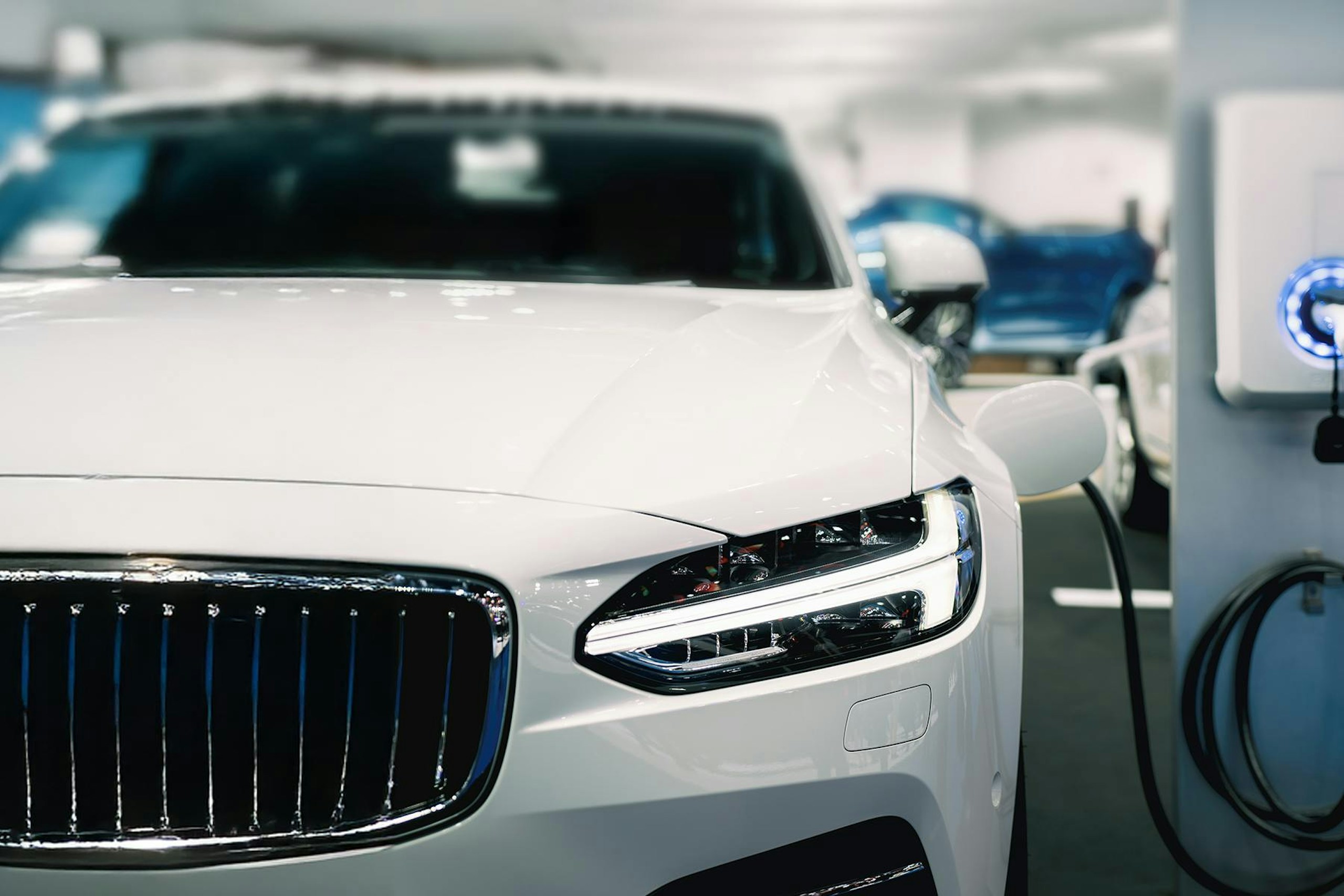 A white car plugged into a silver white charging station for Meltwater's Consumer Insights: Electric Vehicles report.