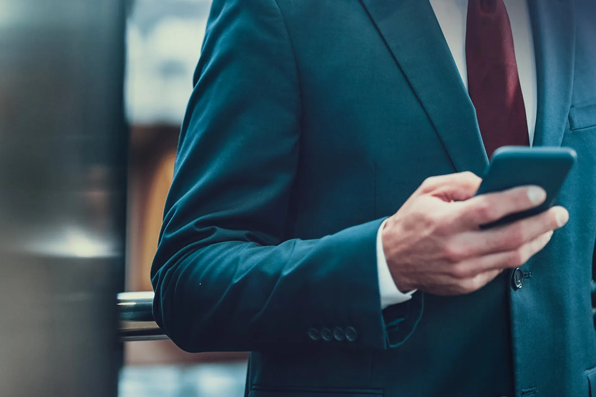 A man in a suit holding a mobile.