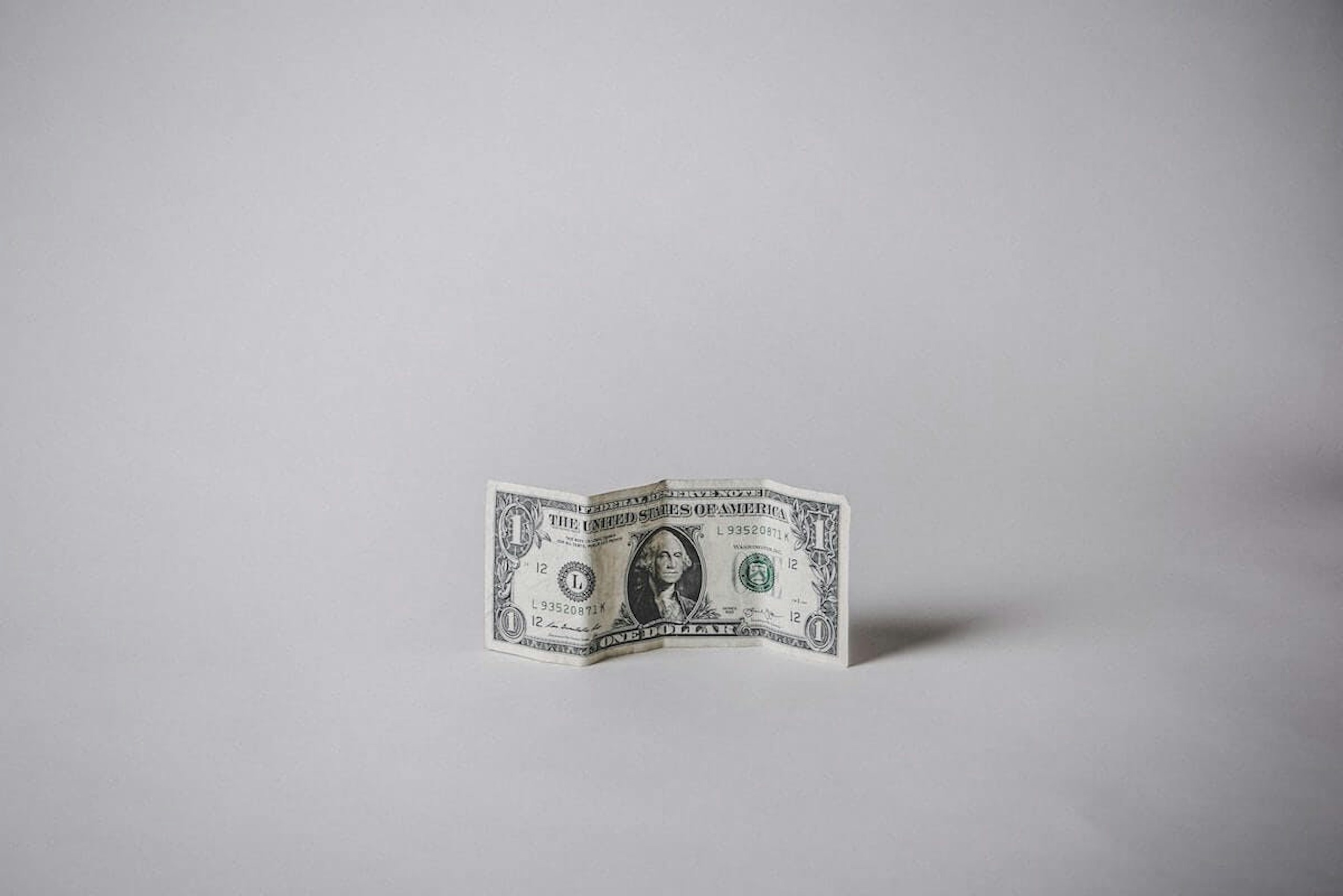 1 US dollar banknote against a white background for showcasing how much media monitoring costs