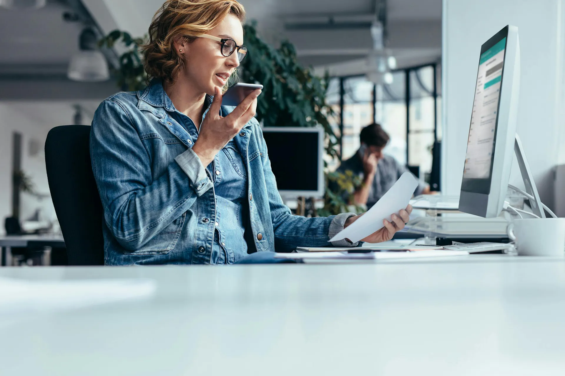 A woman holding a phone sitting at a desk