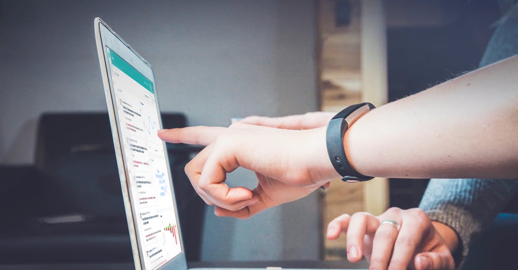 Photo of people pointing at a screen with the Meltwater Media Intelligence Platform on it