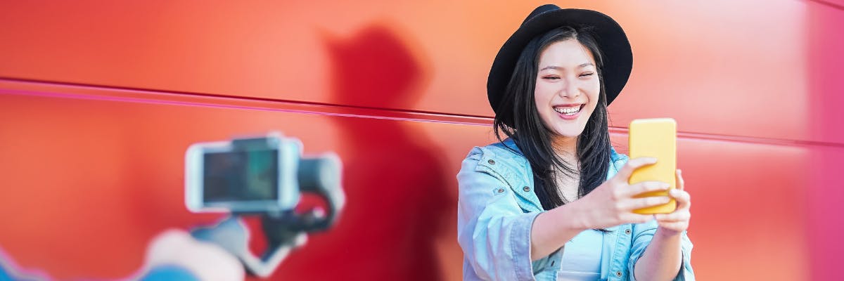 woman hearing a hat and smiling while taking a photo of herself