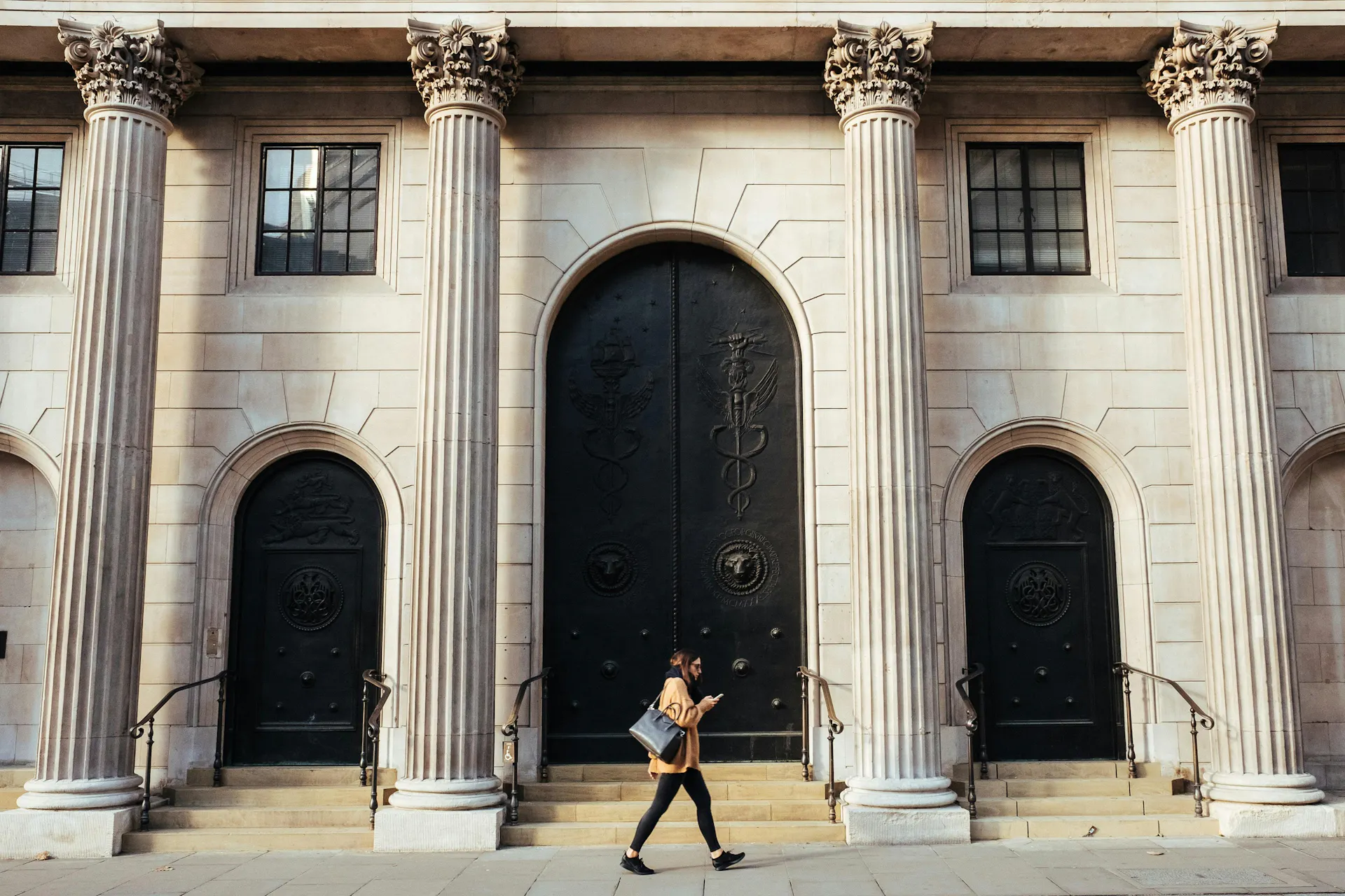person on their phone walking past a bank building