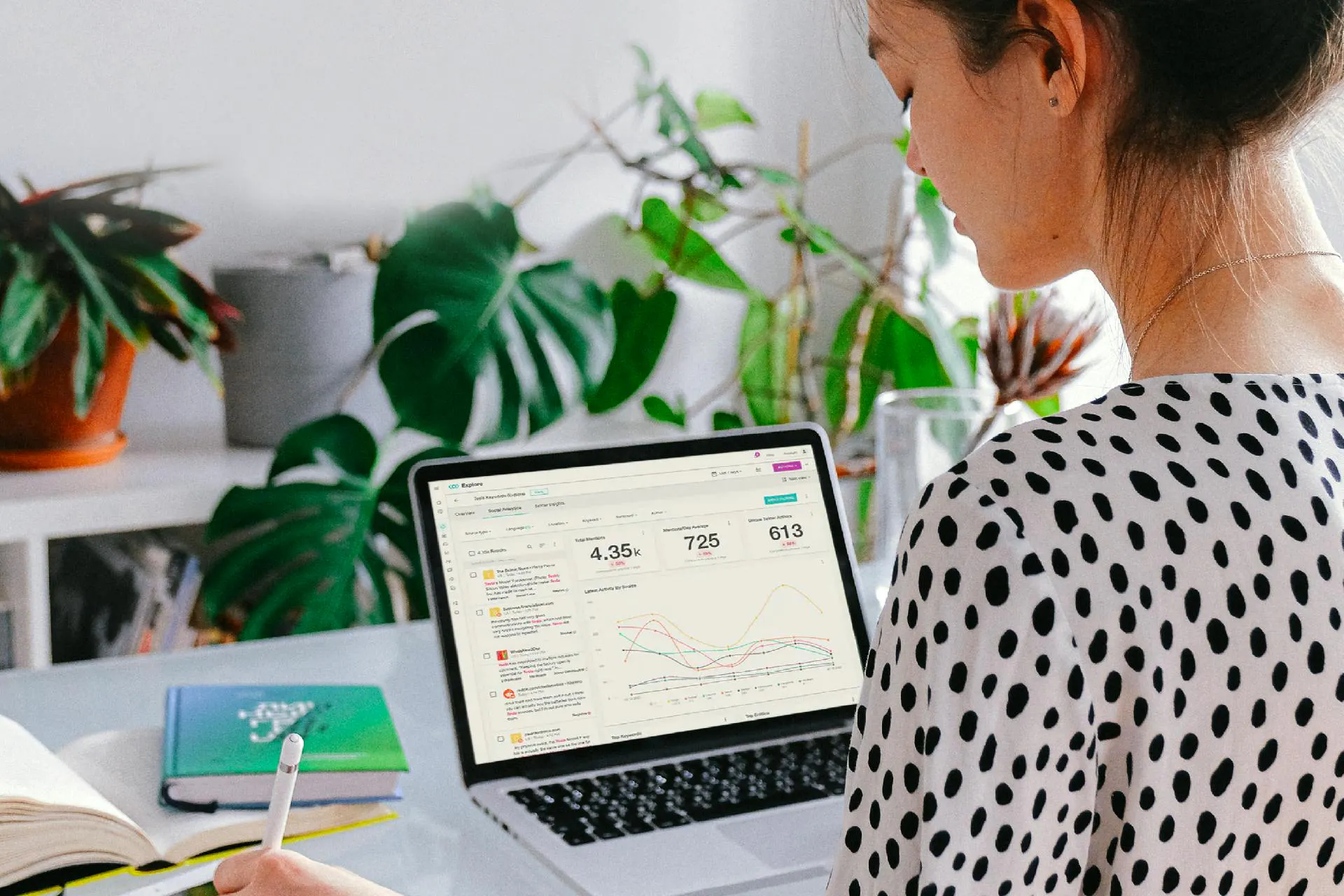 woman with a laptop on desk looking at data analytics on the screen with books on the desk