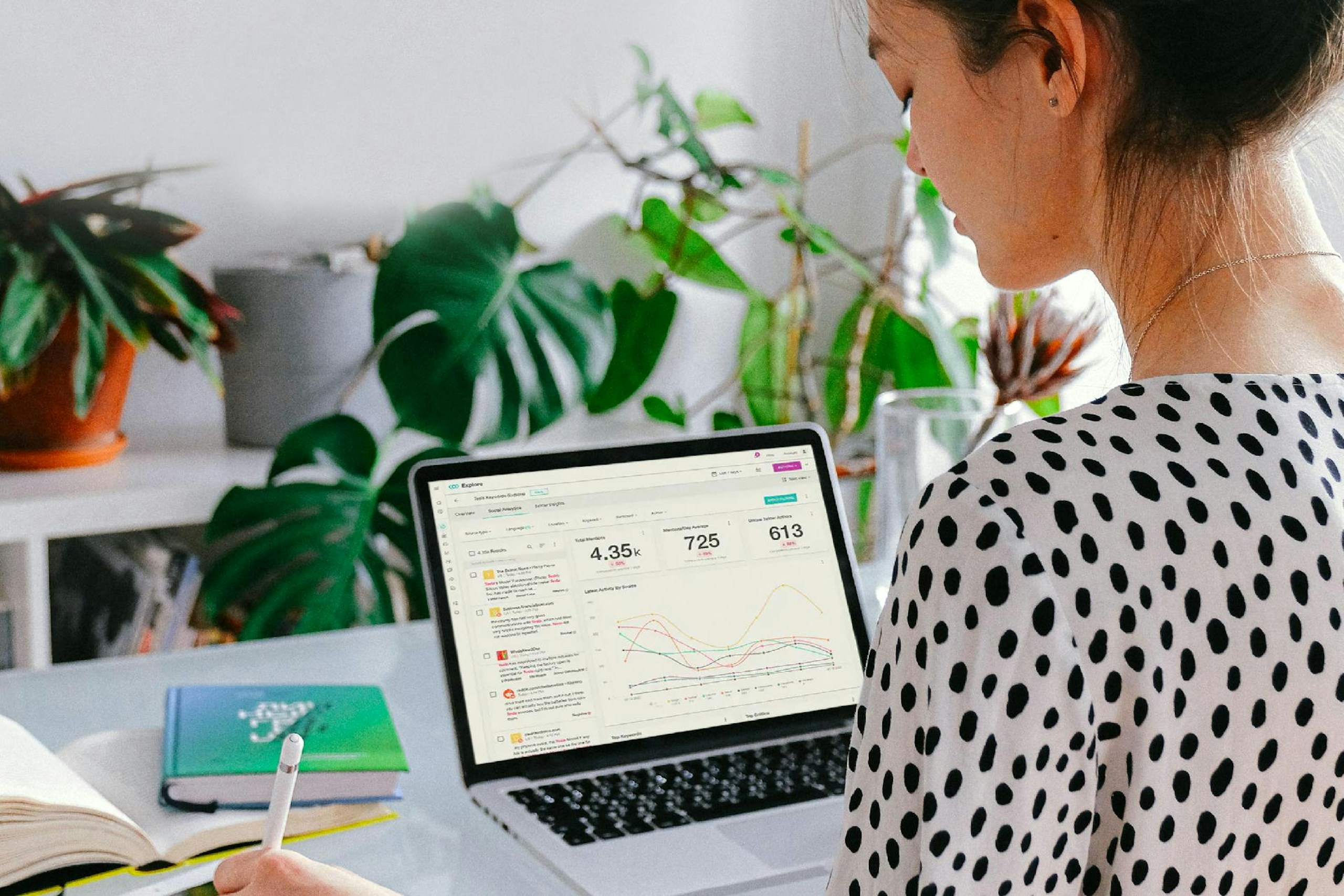 woman with a laptop on desk looking at data analytics on the screen with books on the desk