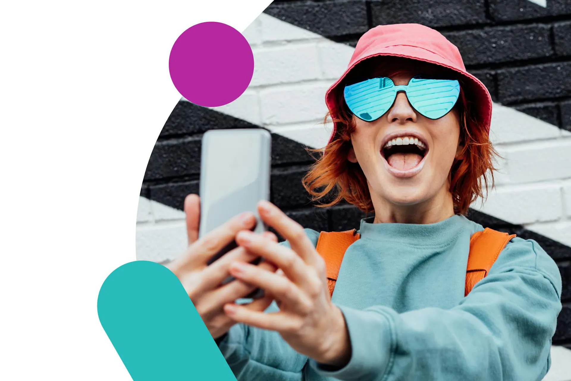 Image showing a young influencer in front of a black and white brick wall, holding a phone. Ultimate guide to influencer marketing