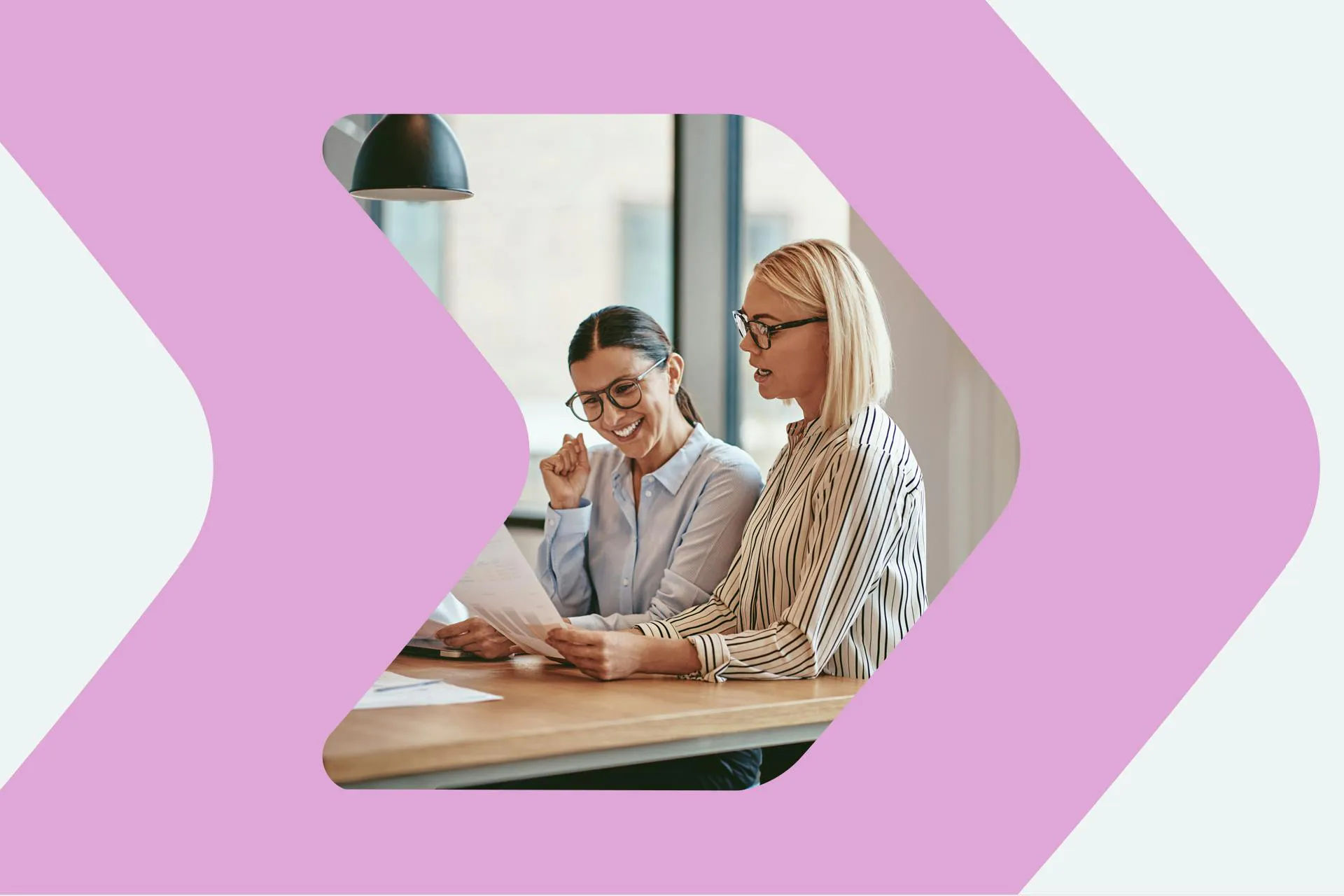 An image of two women in an office having a meeting and looking at a benchmarking report