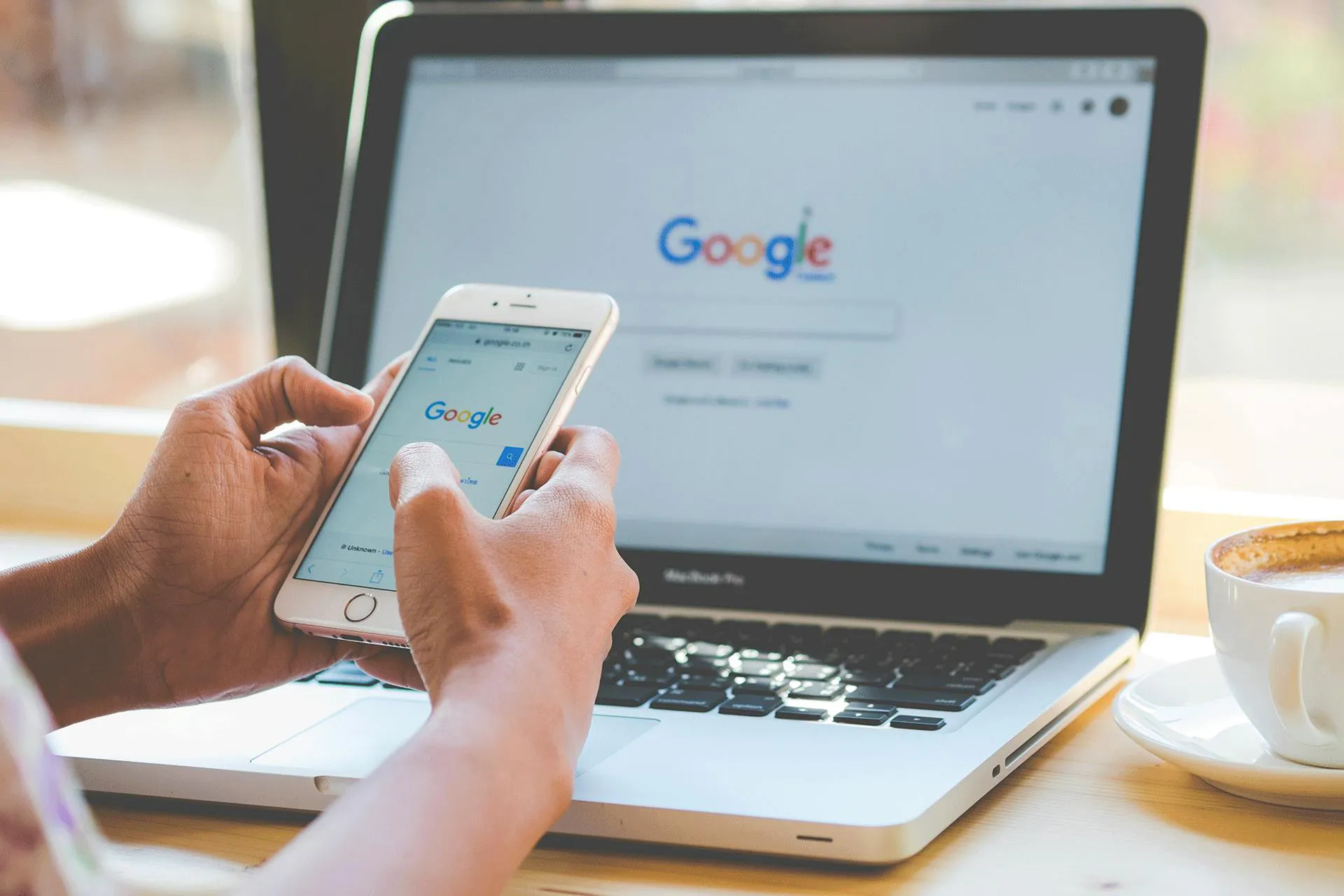 A person searching for google on their mobile and laptop