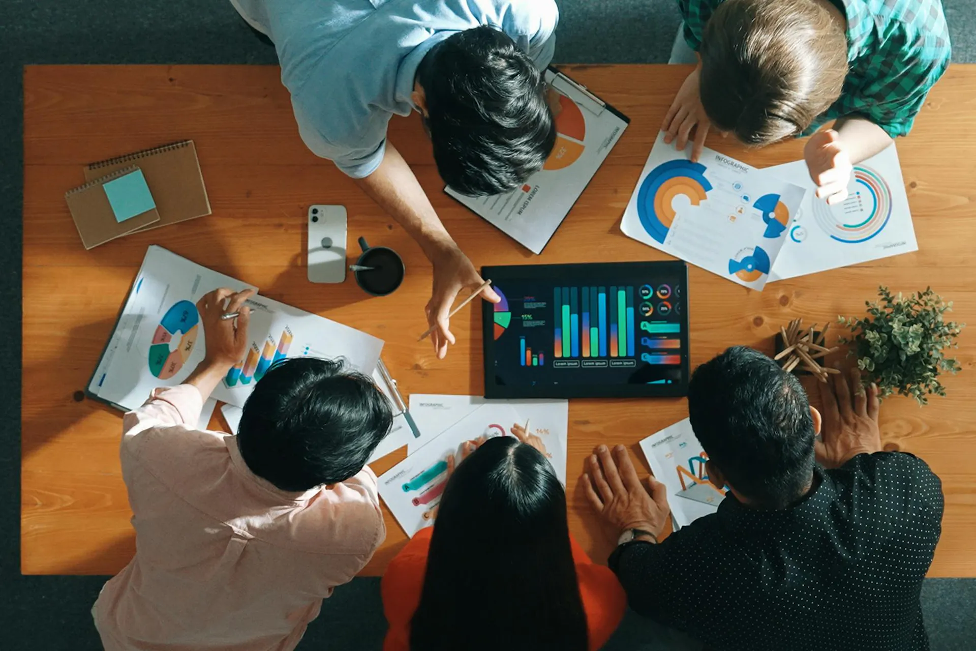 A group of office workers looking at analytics charts on a tablet computer.
