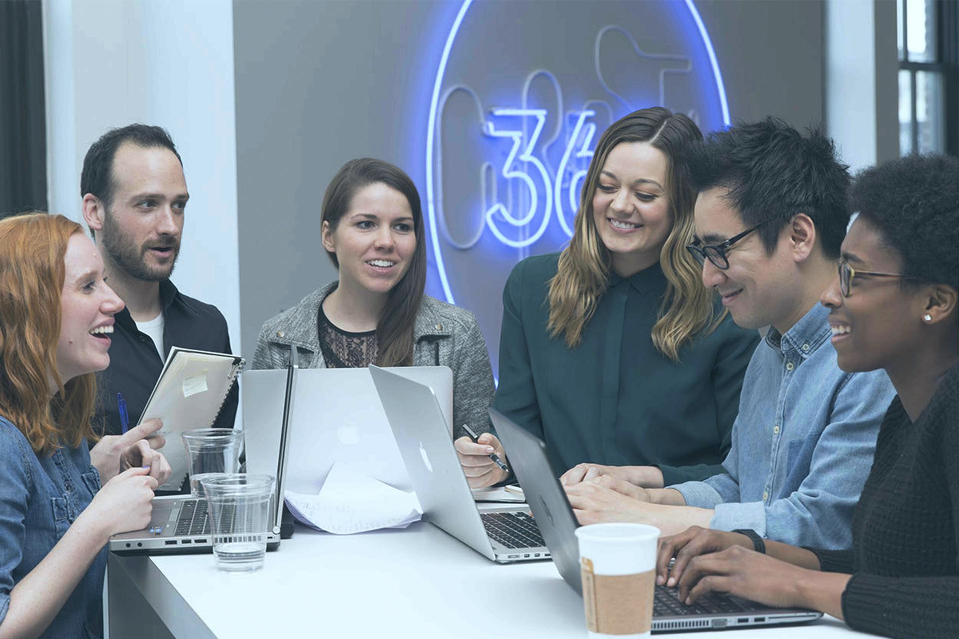 Group of people having a team meeting against the 360i logo