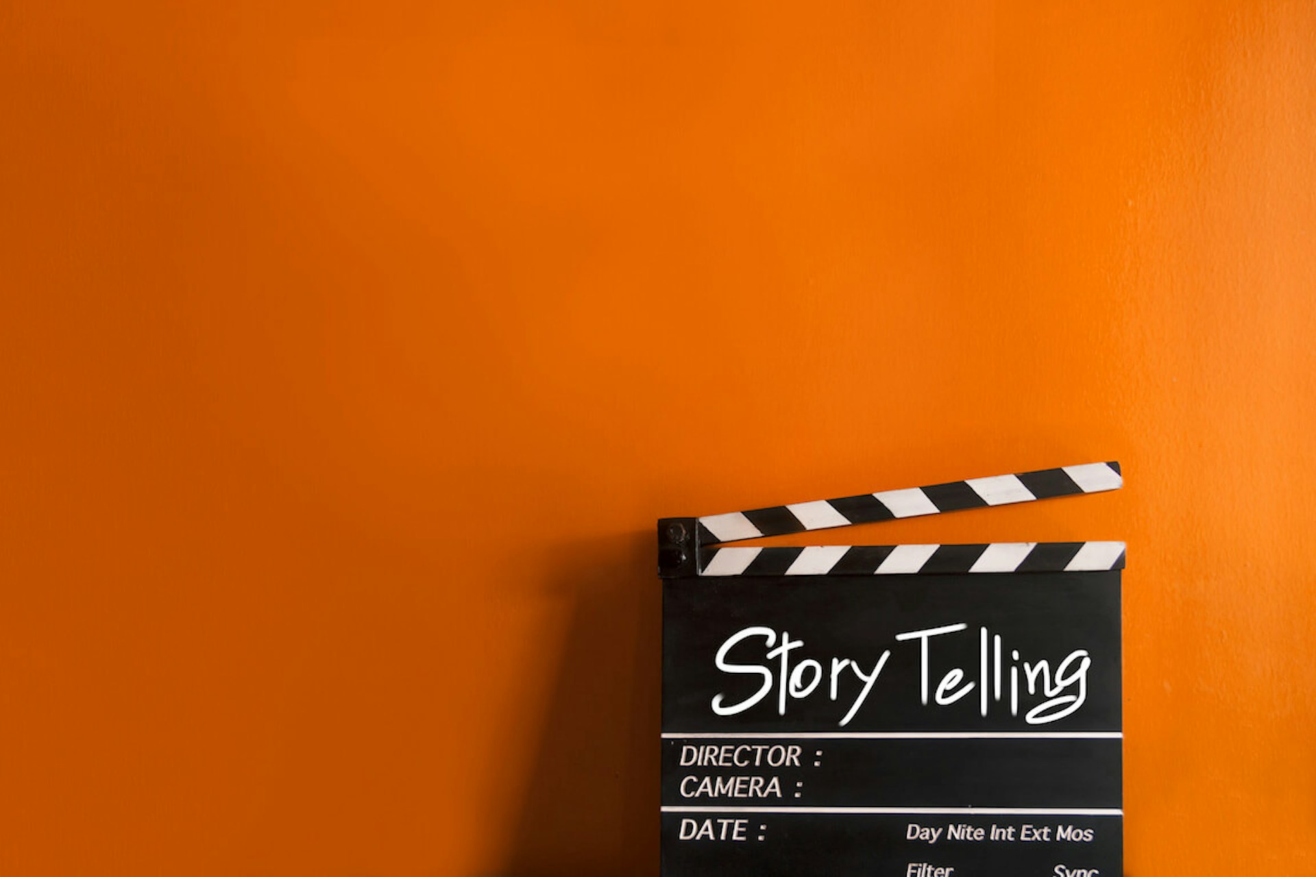 Eine Filmklappe mit der Aufschrift "Story Telling" auf einem orangenen Hintergrund