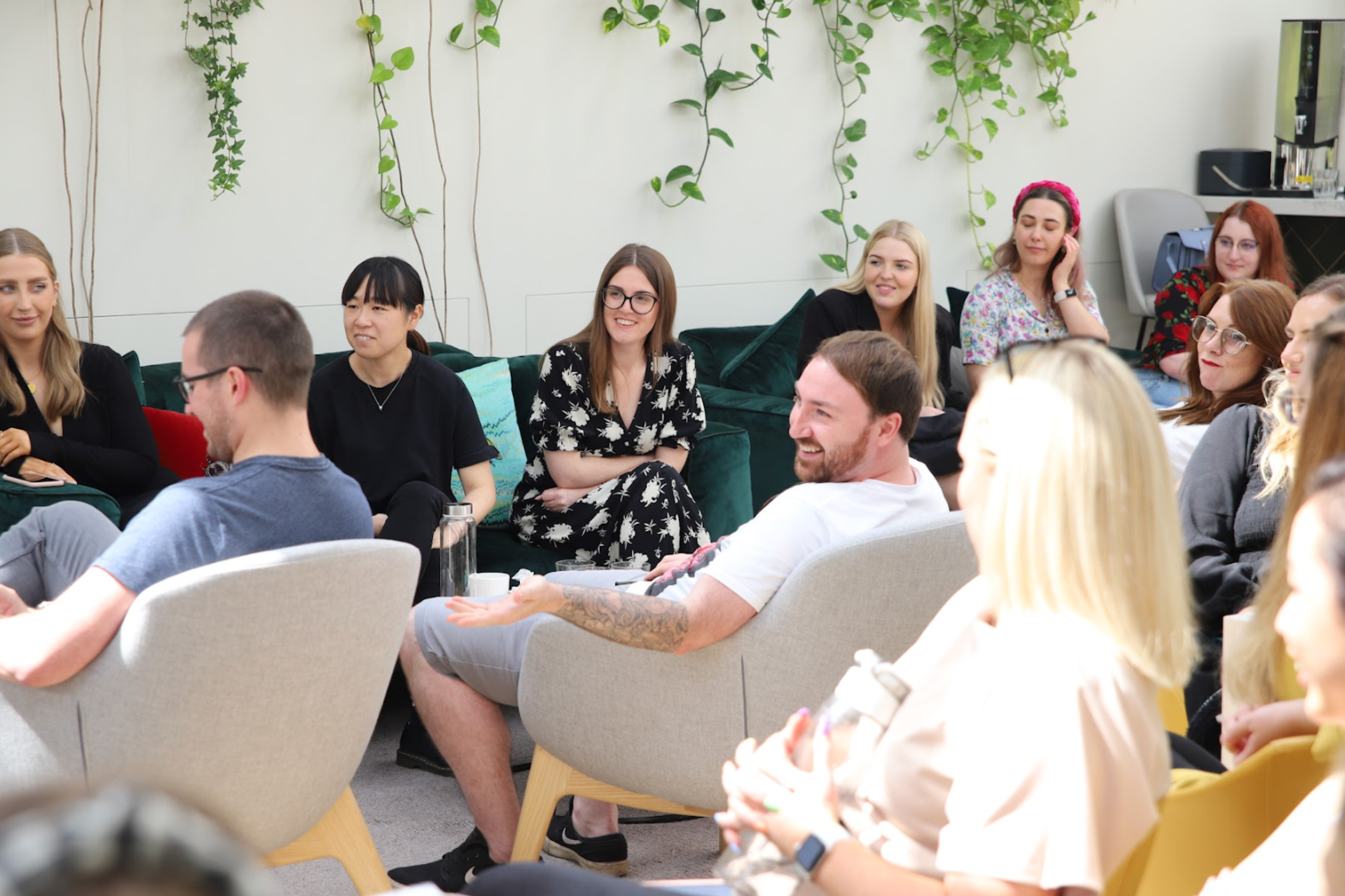 A seated group of people smile in this image for a Meltwater customer story about the PR agency Reboot Online.