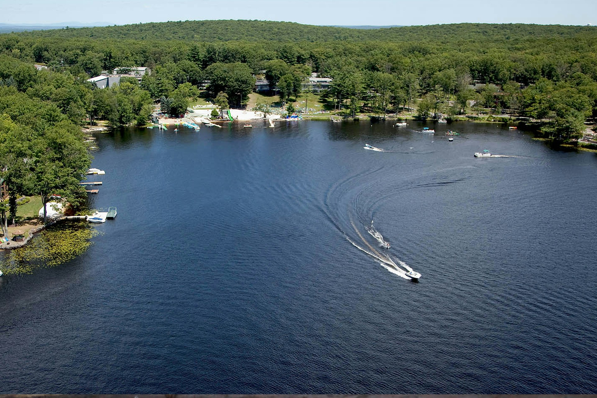 A boat drives across a lake in the Pocono Mountains in this image for a Meltwater customer story for Woodloch Resort.