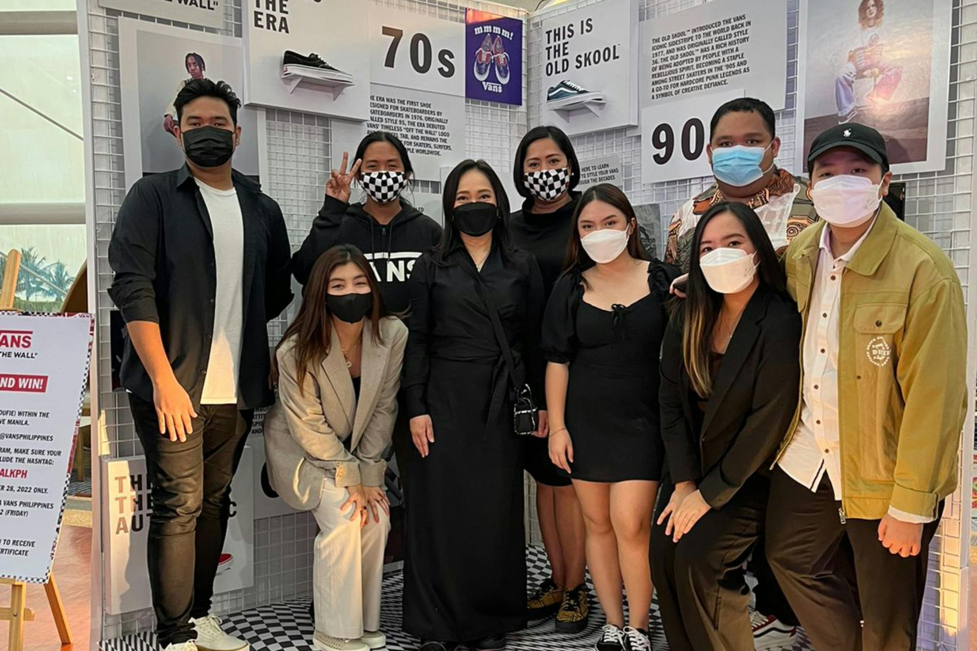 Nine people standing together and smiling for the camera to take a group picture