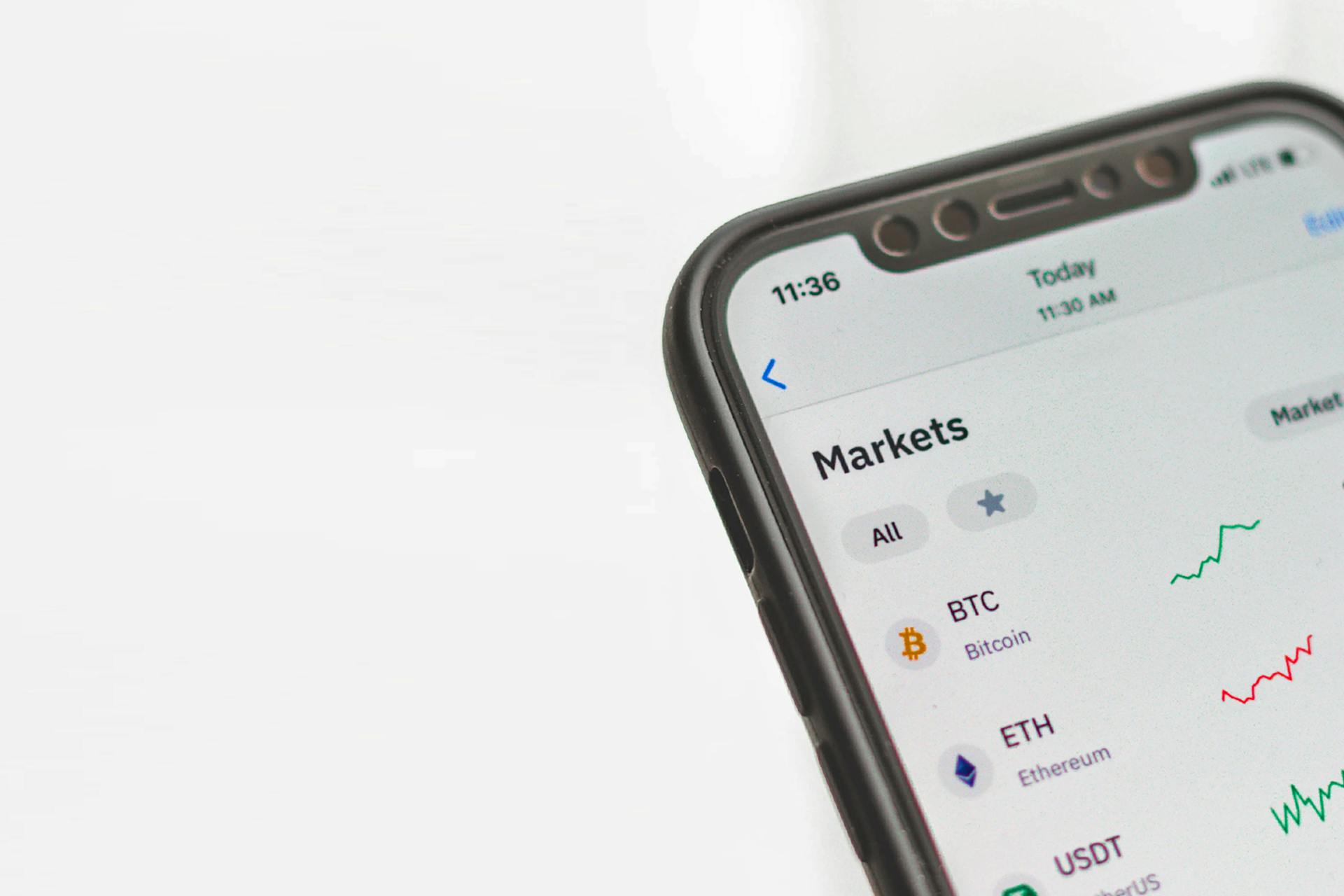A photograph of a cellphone that is showing an app detailing the market performance of various cryptocurrencies