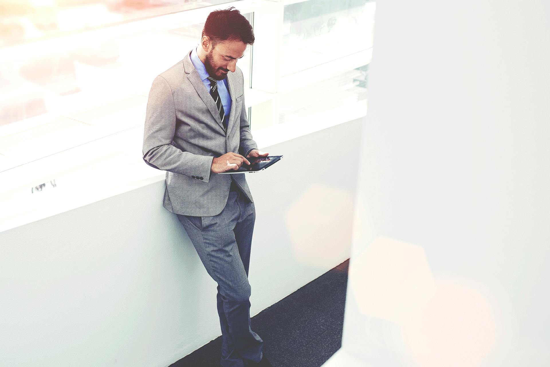 Foto von einem Anzugträger an eine Wand lehnend