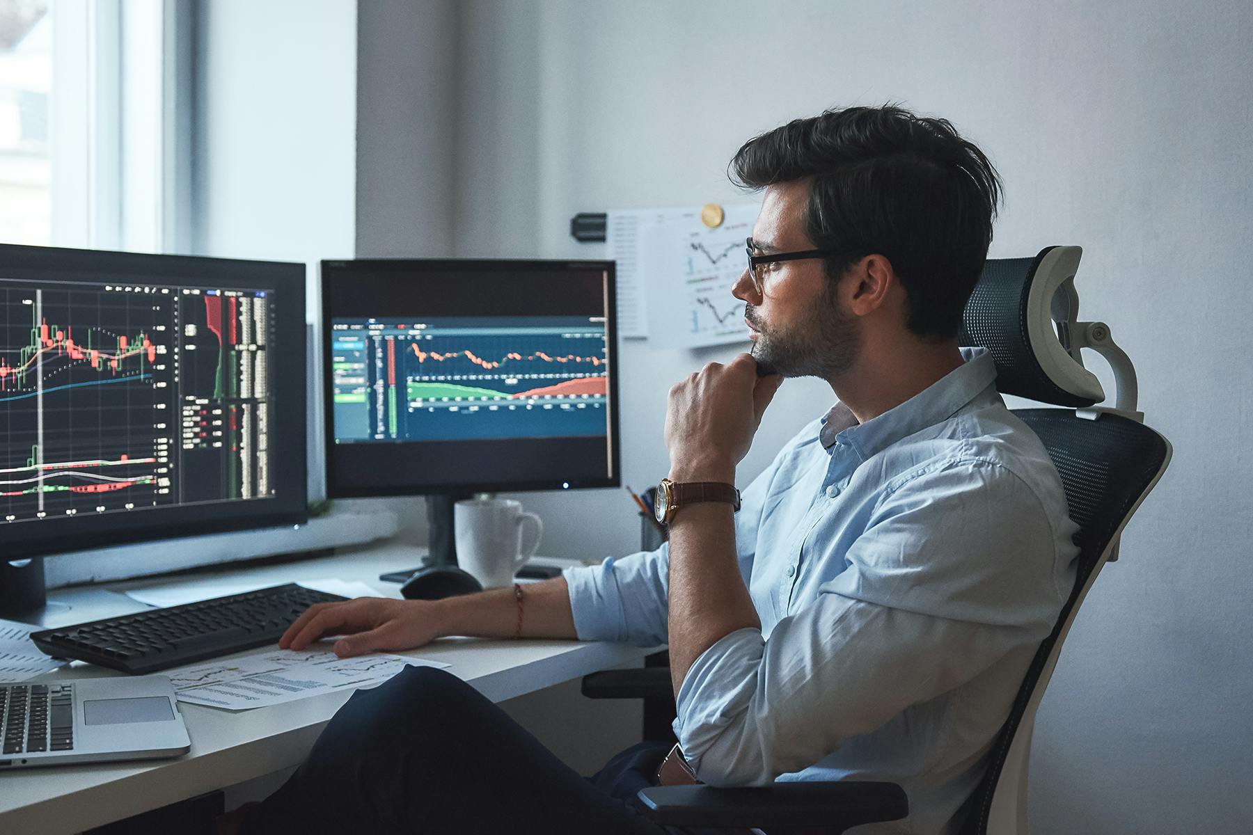 A person sits in an office chair in front of two monitors showing analytics charts for a Meltwater customer story about Luscid.
