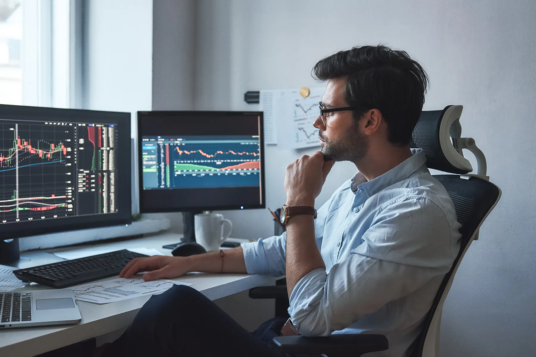 A person sits in an office chair in front of two monitors showing analytics charts for a Meltwater customer story about Luscid.