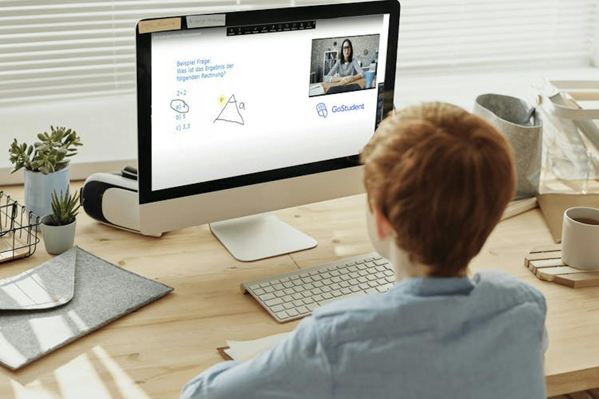 A child sitting at a desk looking at a monitor 