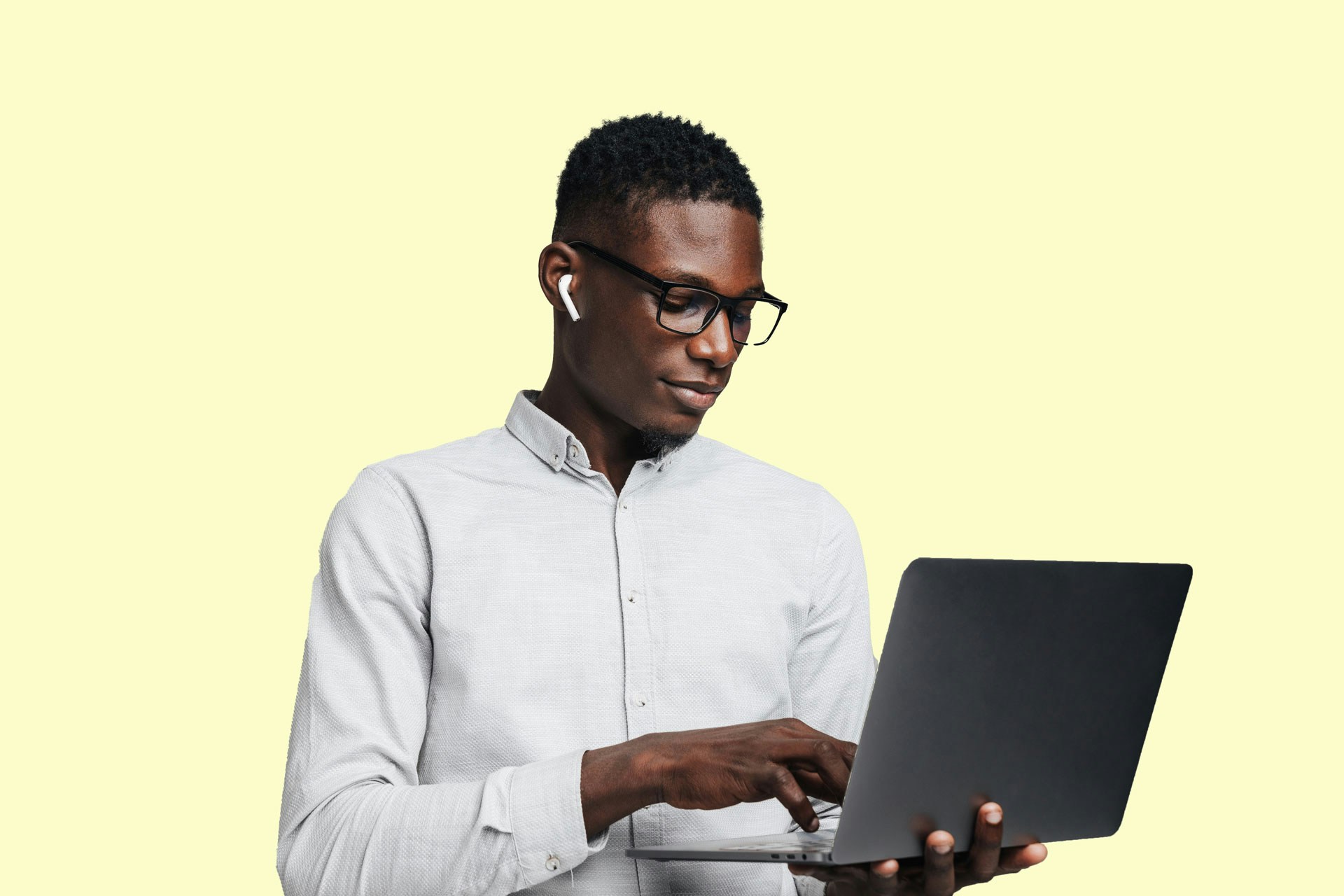 man working on a laptop in front of a yellow background